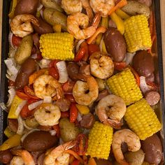 shrimp, corn on the cob, and potatoes are in a baking pan ready to be cooked