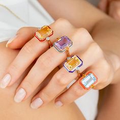 a woman's hand with three rings on it and two different colored stones in the middle