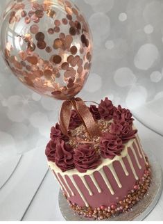 a birthday cake with chocolate frosting and gold decorations on top, sitting on a table next to a large balloon