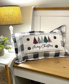 two christmas pillows sitting on top of a wooden table next to a lamp and potted plant