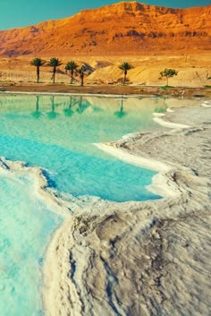 the water is very blue and green in this desert area with mountains in the background