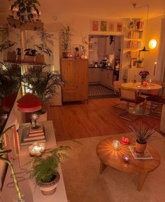 a living room filled with furniture and lots of plants on top of a hard wood floor