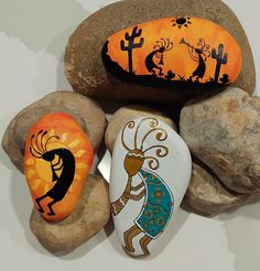 three painted rocks sitting next to each other on top of a white surface with orange and black designs