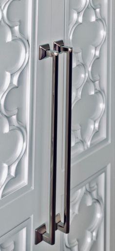 a close up of a door handle on a white door with an intricately designed design