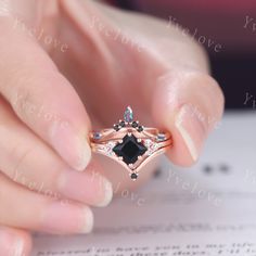 a close up of a person's hand holding an engagement ring with black and white diamonds