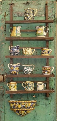 an old wooden shelf filled with lots of different types of cups and saucers on it