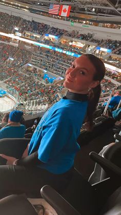 a woman sitting in the stands at an ice hockey game looking up into the sky