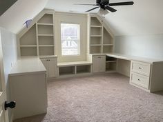 an attic bedroom with built - in shelving and ceiling fan, carpeted floor