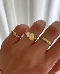 a woman's hand with two gold rings on it and one diamond ring in the middle