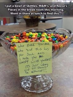 a glass bowl filled with lots of candy on top of a counter next to a sign that says, i put a bowl of skittles mem's and reese's