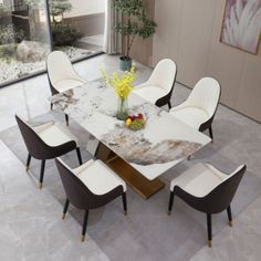 a dining room table with chairs and a vase filled with flowers on top of it