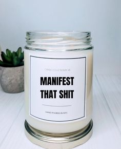 a white candle sitting on top of a table next to a potted plant