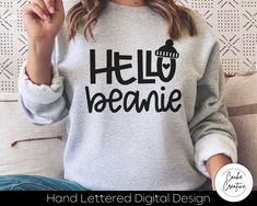 a woman sitting on a couch wearing a sweatshirt that says hello veanne