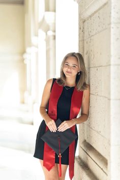 a woman standing next to a wall wearing a red and black dress