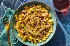 pasta with meat and sauce in a bowl next to a glass of wine on a blue towel