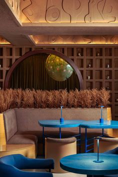 the interior of a restaurant with blue tables and chairs in front of a circular mirror