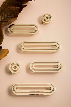 four white paperclips sitting on top of a table next to a leaf