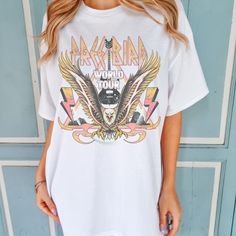 Embark on a retro music journey with the Free Bird World Tour Shirt. Featuring a vintage-inspired design with an eagle, this Comfort Colors Boho T-Shirt is perfect for music enthusiasts. All clothing and accessories from The Southern Thistle are handmade-to-order, just for you! ☺️  SIZING: Tshirts and sweatshirts are unisex, classic fit. Please refer to size chart in listing photos for details. Easy measuring tip: Take your favorite shirt, lay it on a flat surface and measure the width (armpit t Vintage T-shirt With Band Logo For Music Festival, Music-themed Cotton Tops With Graphic Print, Music-themed Cotton Top With Graphic Print, Music-themed Cotton Graphic Top, White Tops With Band Logo For Music Festivals, Retro Tops With Letter Print For Music Festival, Retro Letter Print Tops For Music Festival, Retro Graphic Print Top For Concert, Retro Band Logo Tops For Music Festivals