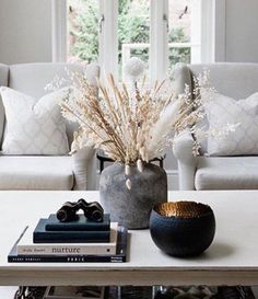 a living room filled with furniture and a white coffee table topped with a vase full of dry grass