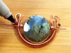 a wire wrapped pendant with a large blue stone on it's end and two copper wires