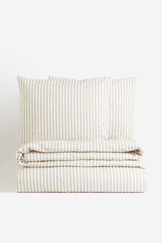 a white and grey striped bed spread with two pillow cases on top of each other