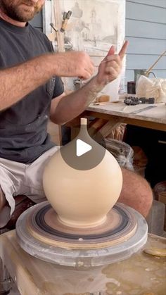 a man sitting on top of a table next to a pottery pot and making something