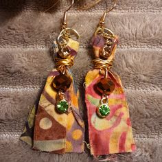 two pairs of earrings are sitting on a piece of fabric