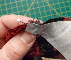 the sewing needle is being used to sew fabric on top of an unbuttoned piece of cloth