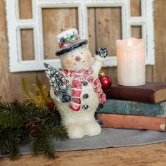 a snowman figurine next to some books and a candle