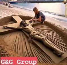 a woman is making a crucifix out of sand on the beach with water in the background