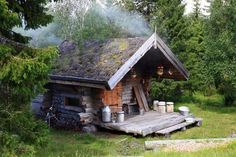 an old log cabin in the woods with pots and pans on it's roof