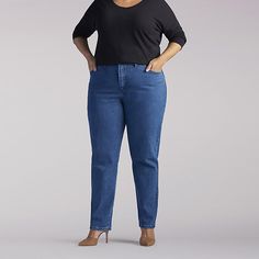 a woman in black shirt and jeans standing with her hands on her hips, looking at the camera