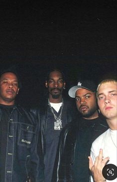 a group of men standing next to each other in front of a black wall with red and blue lights