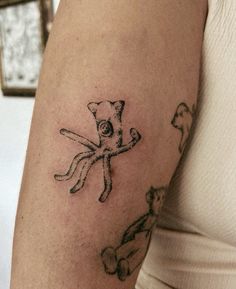 a woman's arm with an octopus and cat tattoo on the left side of her arm