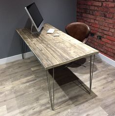 an office desk with a computer on it in front of a brick wall and chair