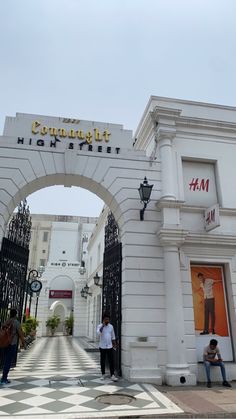 two people are standing in front of the entrance to a shopping mall with an arch