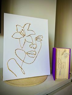 a white card with gold foil on it next to a purple box and a book