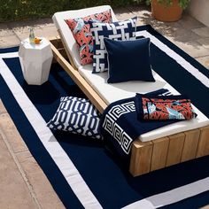 an outdoor day bed with pillows on it in the middle of a patio area next to a potted plant