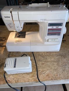 a white sewing machine sitting on top of a wooden table next to a corded phone