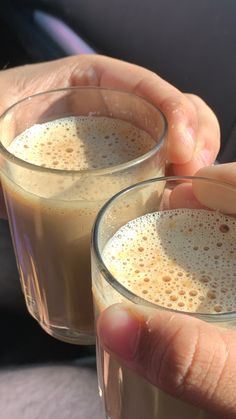 two people holding glasses filled with liquid in their hands