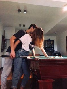 a man and woman kissing in front of a pool table