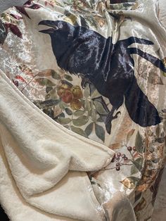 a white robe with a black bird on it's back and floral designs on the fabric