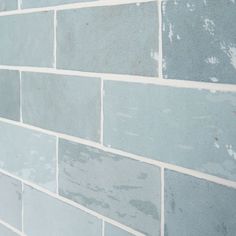 a close up of a blue brick wall with white grouting on the side