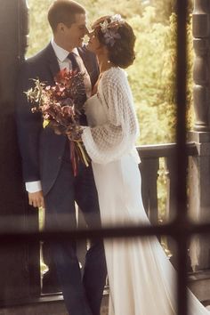 a bride and groom standing on a porch with their arms around each other as they kiss