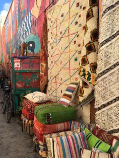 colorful carpets and rugs are lined up on the side of a building with bicycles parked nearby