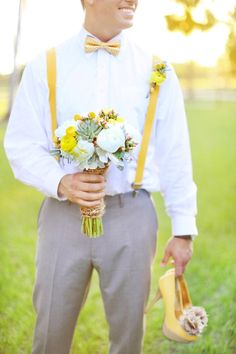 a man in a white shirt and yellow suspenders is holding a bouquet of flowers