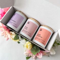 three candles sitting in a box next to flowers