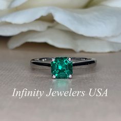 a close up of a ring with an emerald colored stone on the front and side