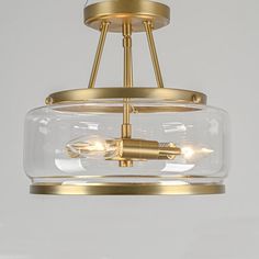 a glass and brass light fixture with two lights on each side, hanging from the ceiling