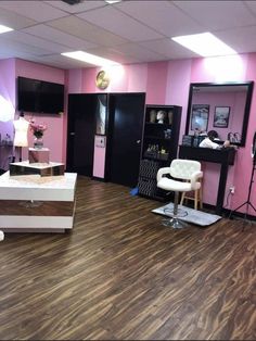 a hair salon with pink walls and wood flooring, white chairs and lights on the ceiling